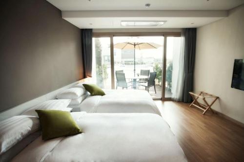 a hotel room with three beds and a patio at The Grand Sumorum in Seogwipo