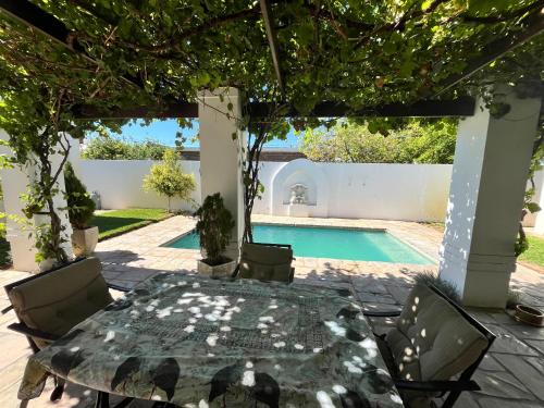 a patio with a table and chairs and a swimming pool at Toni's Cottage in Graaff-Reinet