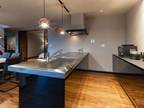 een keuken met een roestvrijstalen wastafel en een woonkamer bij Kubikai in Itoshima