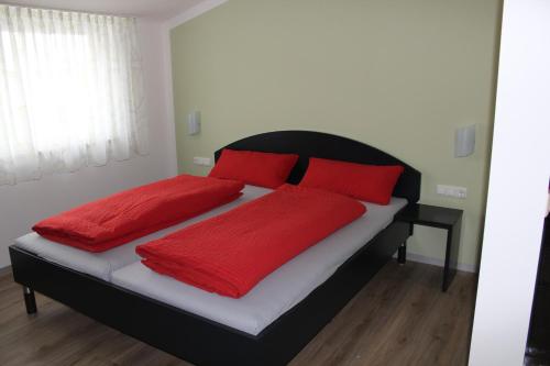 een slaapkamer met een bed met rode kussens erop bij Helmers Gästehaus in Gempfing
