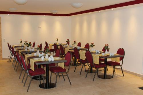 a conference room with long tables and red chairs at Helmers Gästehaus in Gempfing