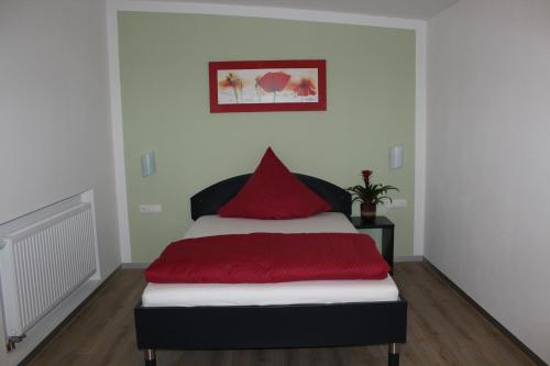 a bedroom with a bed with a red pillow at Helmers Gästehaus in Gempfing