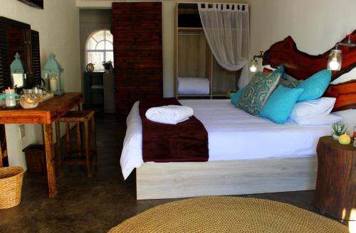 a bedroom with a large bed and a table at Waterfall Guesthouse in Rustenburg