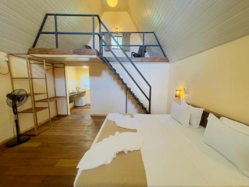 a bedroom with a bed and a spiral staircase at Beach Cabanas Hiriketiya in Hiriketiya