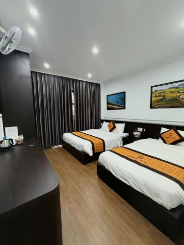 a hotel room with two beds and a desk at Friendly Hotel in Dồng Văn