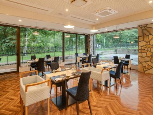 a restaurant with tables and chairs and large windows at Wan Wan Paradise Premier Yamanakako in Yamanakako