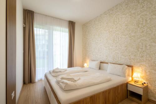a bedroom with a large white bed with a window at SzemesBay Apartment by BLTN in Balatonszemes