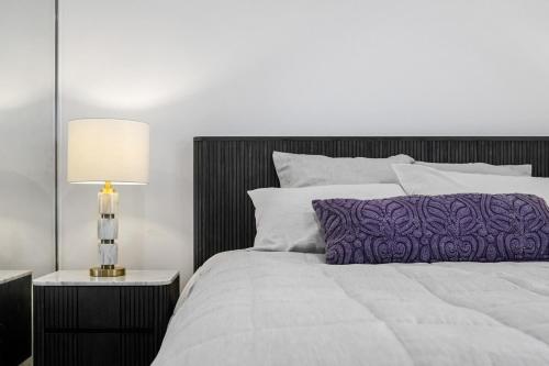 een slaapkamer met een groot bed met een paars kussen bij Serene Designer Stay in Sydney