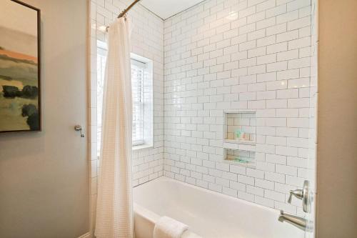 a white tiled bathroom with a tub and a window at Coach`s Corner in Savannah