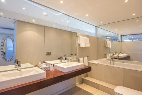 a bathroom with two sinks and a large mirror at Infinity Self Catering Apartments in Bloubergstrand