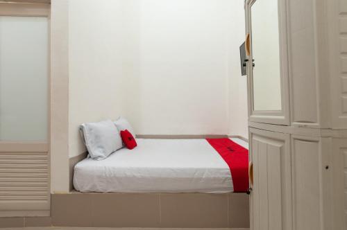 een kleine kamer met een bed met een rode deken bij RedDoorz near UISU teladan Medan in Medan
