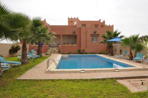 a swimming pool in front of a house with palm trees at Dar El Ferdaous in Al Medou