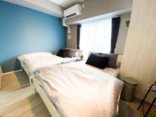 two twin beds in a room with blue walls at 最大4名宿泊 名古屋駅近 地下鉄徒歩5分 お部屋貸し切り 無料Wi-Fi TypeB in Nagoya