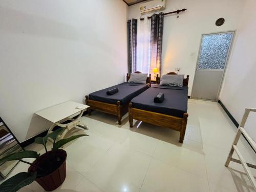 Una habitación con dos camas y una mesa y una ventana. en Lucky Beach Mirissa, en Mirissa