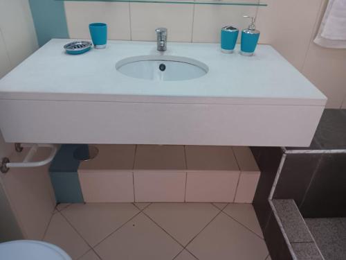 een badkamer met een witte wastafel met blauwe kopjes erop bij Vila Verde House in Santa Maria