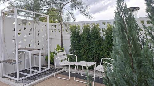 a patio with white chairs and a table and a fence at Baanjaifu บ้านใจฟู in Mukdahan