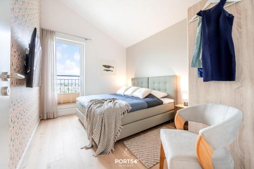 a bedroom with a bed and a chair and a window at Penthouse Kapitänskajüte, App 25 Olpenitz in Olpenitz