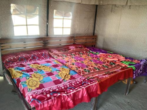a bed in a room with a colorful blanket on it at Stayguru Patgar Tent in Dhordo
