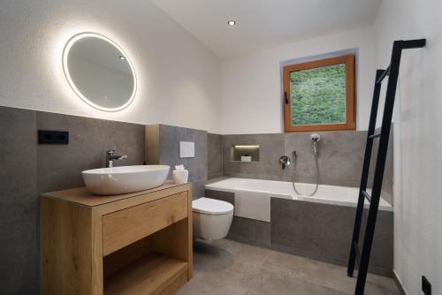 a bathroom with a sink and a tub and a toilet at Chalet Florian in Kirchberg in Tirol