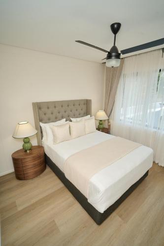 a bedroom with a large white bed with a ceiling fan at Duplex in Vainona in Harare