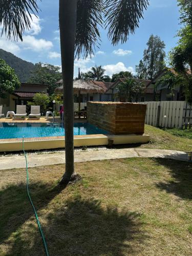 a house with a swimming pool and a palm tree at Escape-Cabins in Ko Lanta