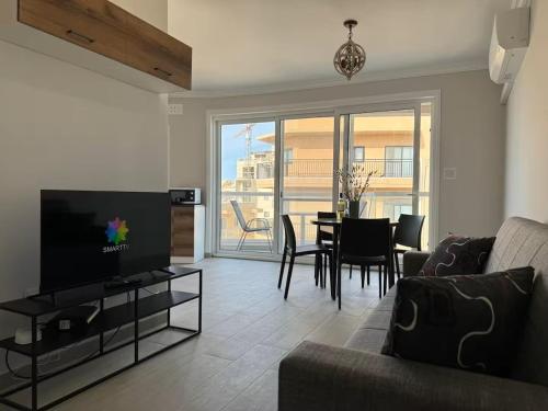 a living room with a television and a table with chairs at New and Modern Two Bedroom Apartment with Sea View in Il-Ħamrija