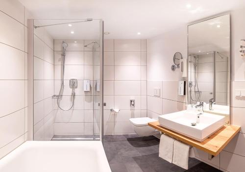 a bathroom with a shower and a sink and a toilet at Tulip Inn Ludwigshafen City in Ludwigshafen am Rhein