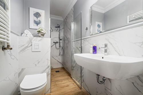 a white bathroom with a sink and a toilet at Pałac nad Jeziorem in Chociwel