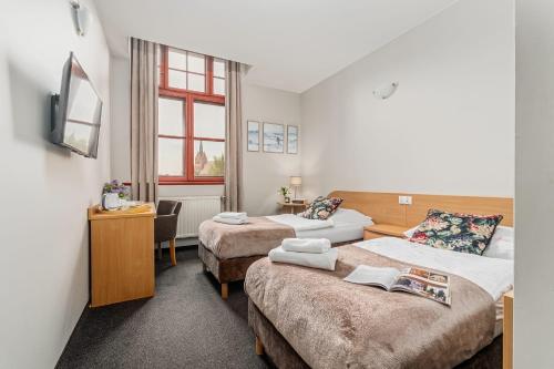 a hotel room with two beds and a desk at Pałac nad Jeziorem in Chociwel