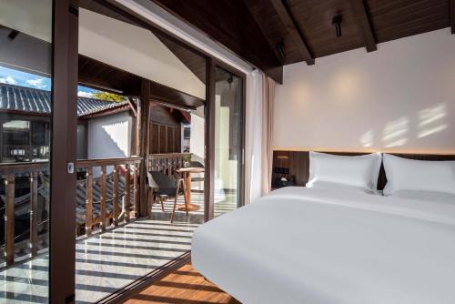 ein Schlafzimmer mit Bett und Balkon in der Unterkunft Golden Dragon's Mountain Glow Inn Chinese Style Courtyard of Lijiang Ancient Town English Speaking Service Close to main streets near by Dashiqiao Sifang Street,Big Water Wheels We offer private car service,tickets purchasing services in Lijiang