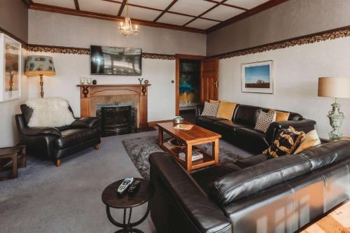 a living room with leather furniture and a fireplace at Timata Ora - 7BR family home in prime location in New Plymouth