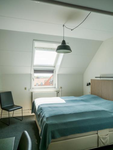 a bedroom with a bed and a chair and a window at Støberiet in Svendborg