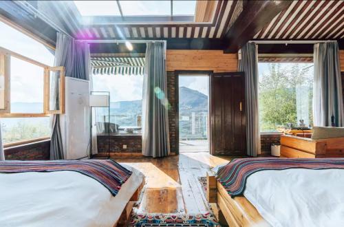 een slaapkamer met 2 bedden en grote ramen bij 松潘怿宿古道牧风民宿Yisu in Songpan