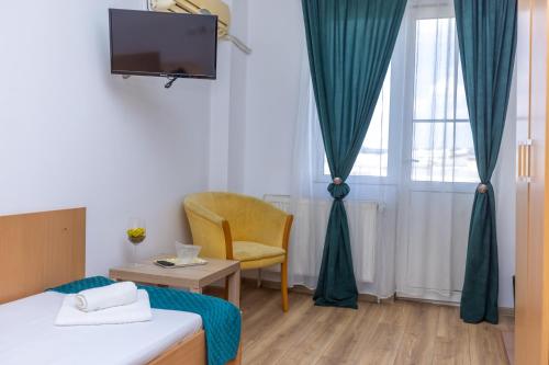 a hotel room with a bed and a chair and a tv at Hotel Sir Gara de Nord in Bucharest
