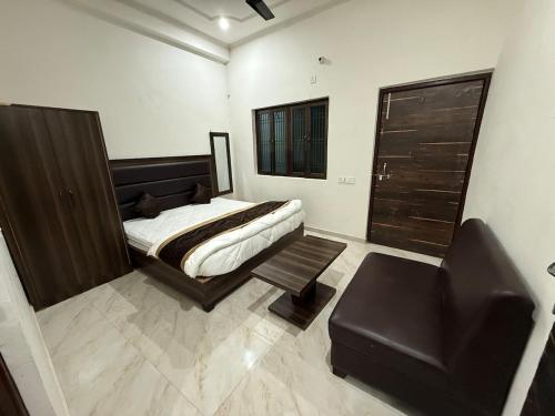 ein Schlafzimmer mit einem Bett, einem Sessel und einer Couch in der Unterkunft Grand Vista Kashi 2BHK Home in Varanasi
