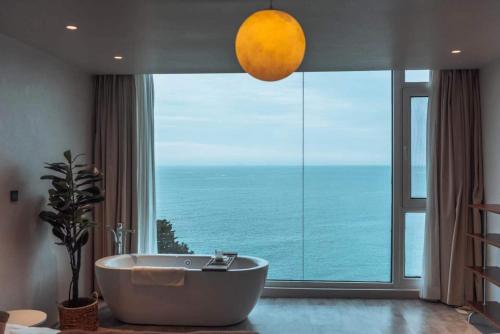 een badkamer met een bad voor een groot raam bij Qingdao Momer Cliff Ocean View Villas in Qingdao