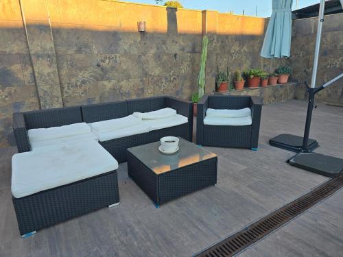 a patio with two wicker furniture and a table at Piscina climatizada jacuzzi sauna y gym privados para 15 con metro in Picassent