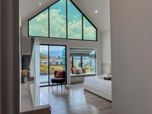 a bedroom with a bed and a large window at Gaia Luxury Pool Villa Khao Yai in Ban Bung Toei