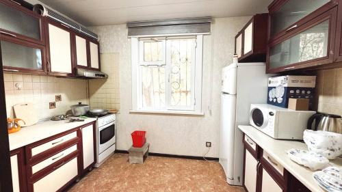 a kitchen with a white refrigerator and a window at Apartments and rooms in Tashkent in Tashkent