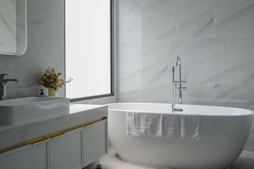 a white bathroom with a tub and a sink at Gaia Luxury Pool Villa Khao Yai in Ban Bung Toei