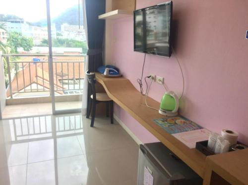 Zimmer mit einem Schreibtisch, einem TV und einem Balkon. in der Unterkunft Baan KetKaew GuestHouse 1 in Patong Beach