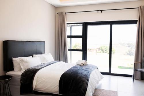 a bedroom with a large bed and a large window at 3BR Drakensberg Retreat, Mountain Views and Braai in Ardmore