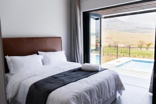 a bedroom with a bed and a view of a pool at Luxury 4BR Drakensberg Home Private Pool and Braai in Champagne Valley