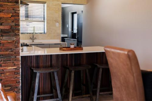 a kitchen with three bar stools and a counter top at Luxury 4BR Drakensberg Home Private Pool and Braai in Champagne Valley