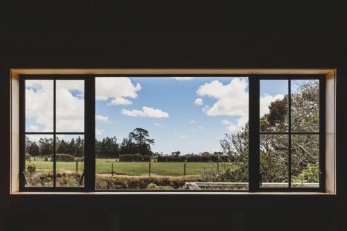 a window with a view of a field through it at The River Retreat - off the grid escape in Inglewood