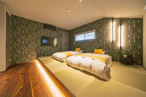 Un dormitorio con dos camas y un televisor en la pared. en 舟屋 栄-Funaya Sakasu-, en Kameshima