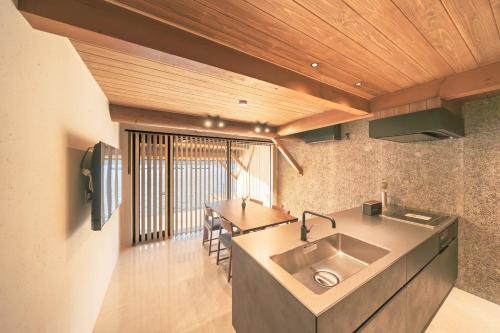 Una cocina con fregadero y techo de madera. en 舟屋 栄-Funaya Sakasu-, en Kameshima