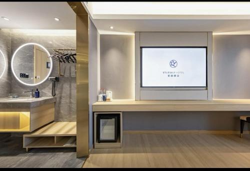 a bathroom with a sink and a tv on a wall at Xingcheng Beijing Huilongguan Jishuitan Hospital Hotel in Beijing