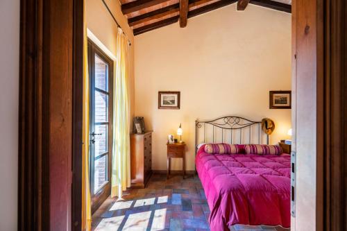 ein Schlafzimmer mit einem Bett mit einer lila Tagesdecke in der Unterkunft Il Castagno Toscana in Campiglia Marittima