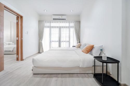 a white bedroom with a large bed and a window at Haus Ekkamai 2 in Klong Toi